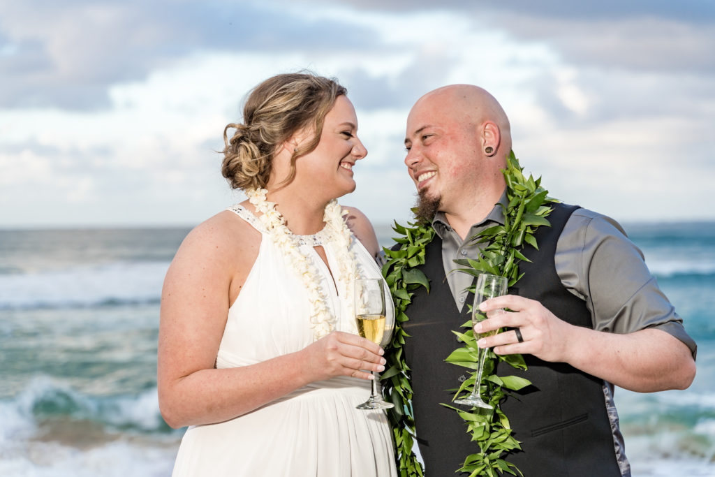 Husband and wife drinking champagne after wedding in Hawaii.