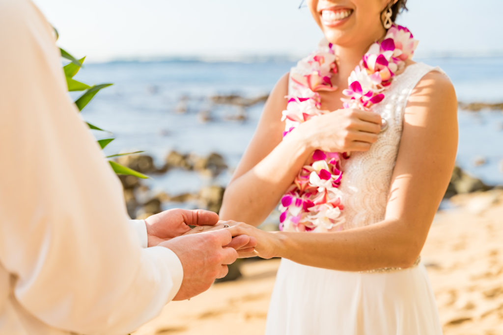 Groom putting wedding ring on Bride.