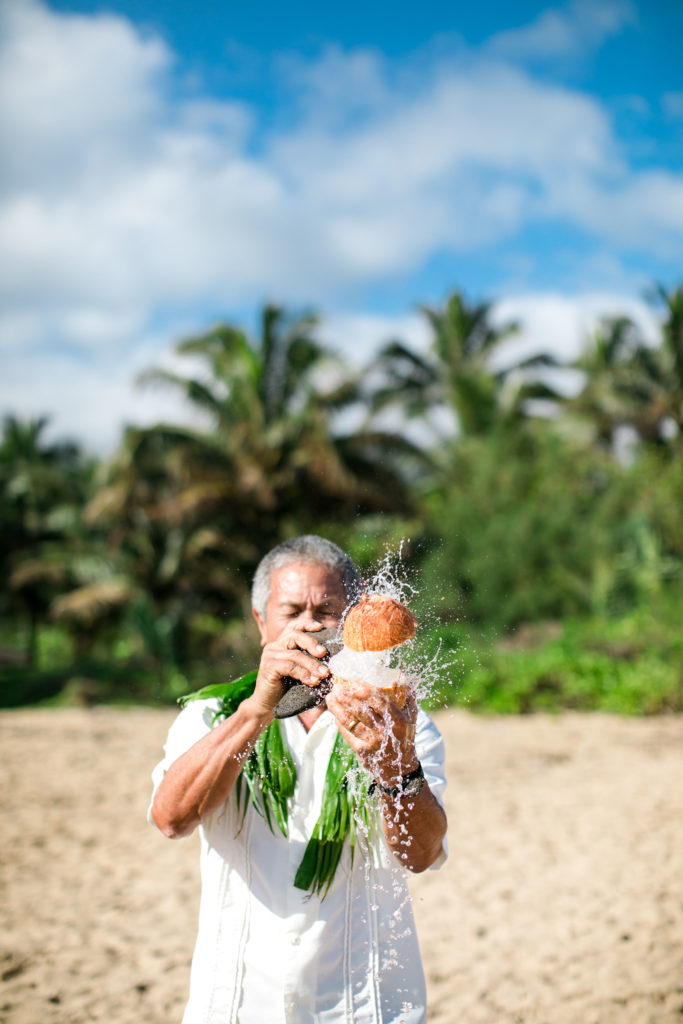 Slicing a coconut on the beach.