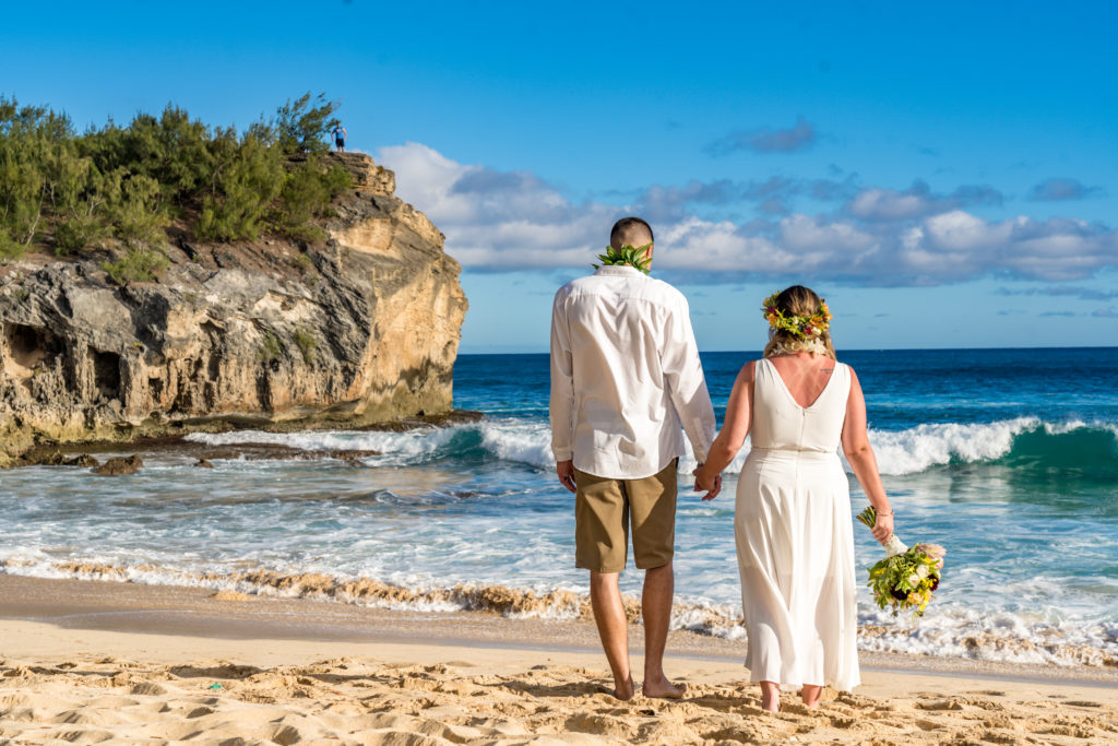 Bride and groom walking down the beach.
