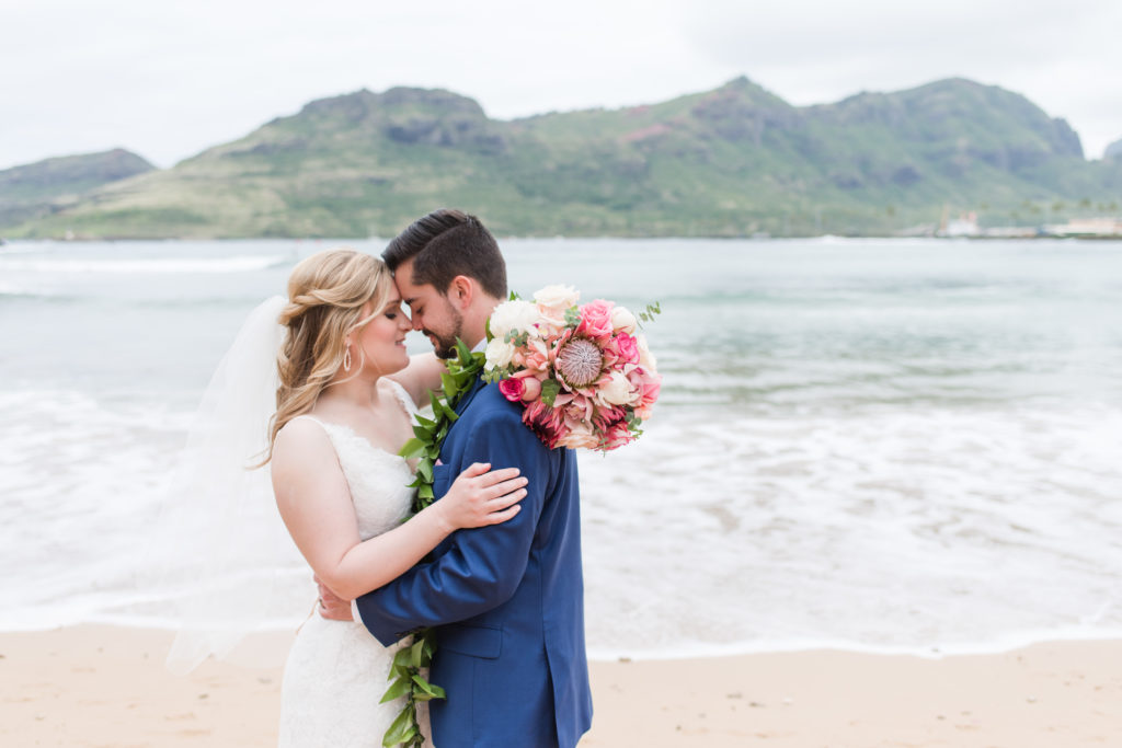 Bride and groom embrace on the beach in Kauai.
