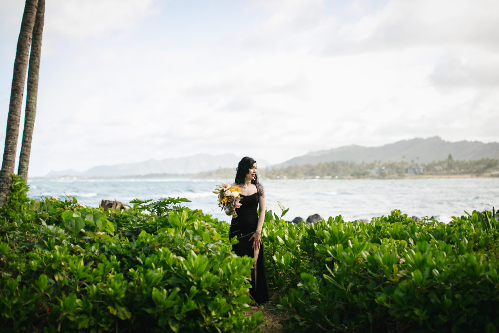 Bride posing for photo in front of the ocean.