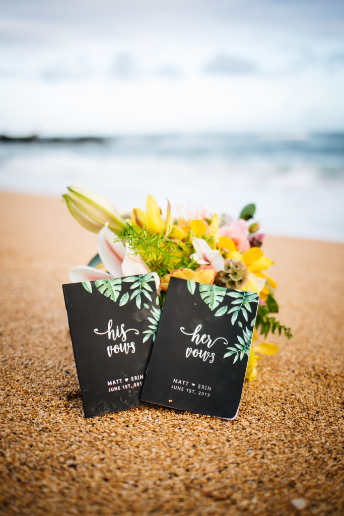 His and hers vow books in sand.