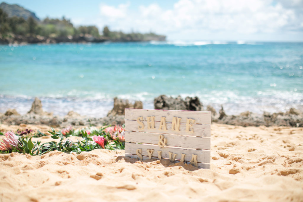 Wooden sign for Shane and Sylvia's wedding on the beach.