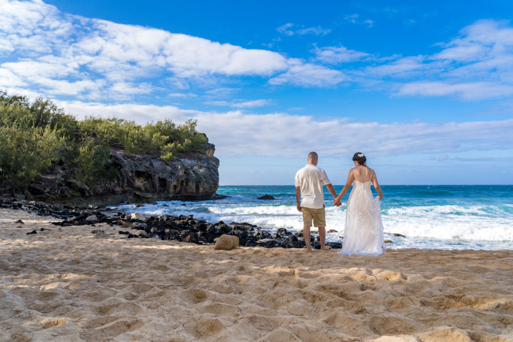 Bride and groom walking on the beach.