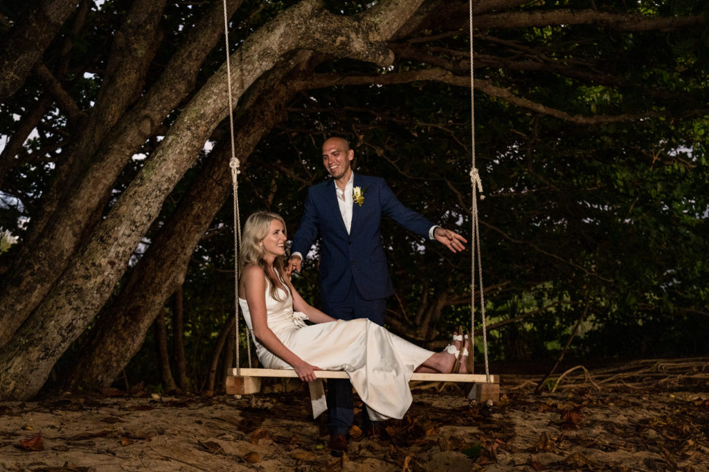 Bride and groom on the beach under a tree.