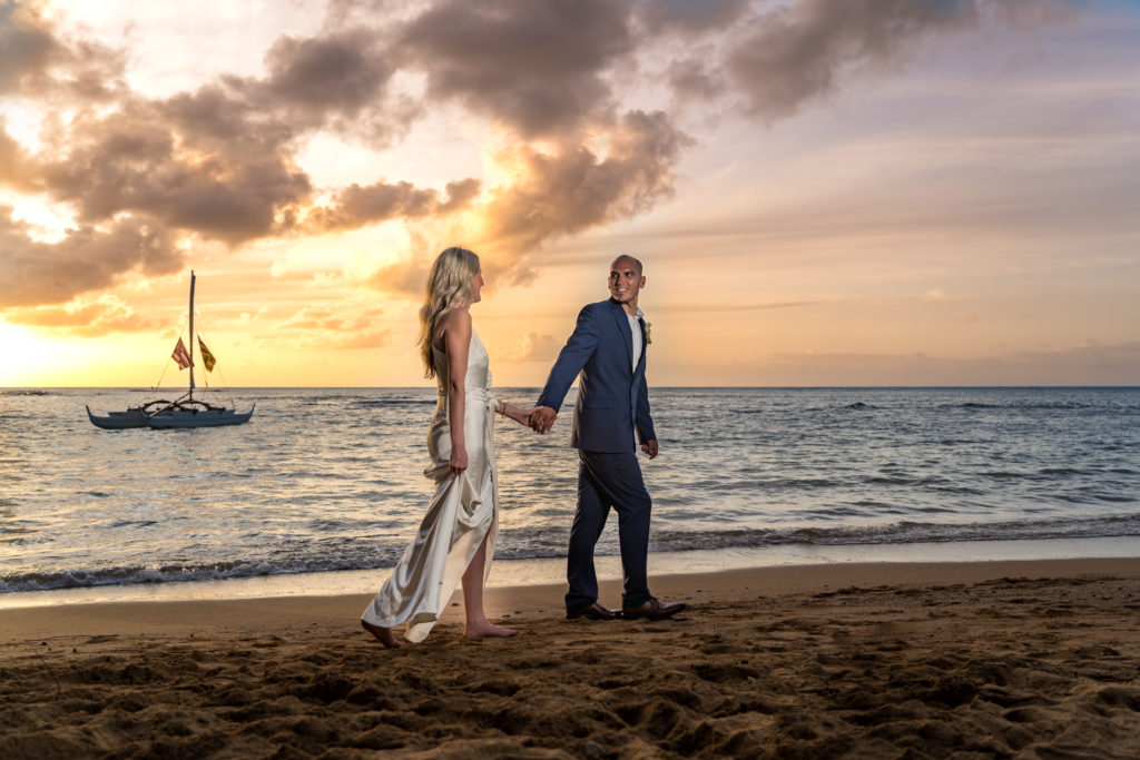 Bride and groom walking on the beach in Kauai.