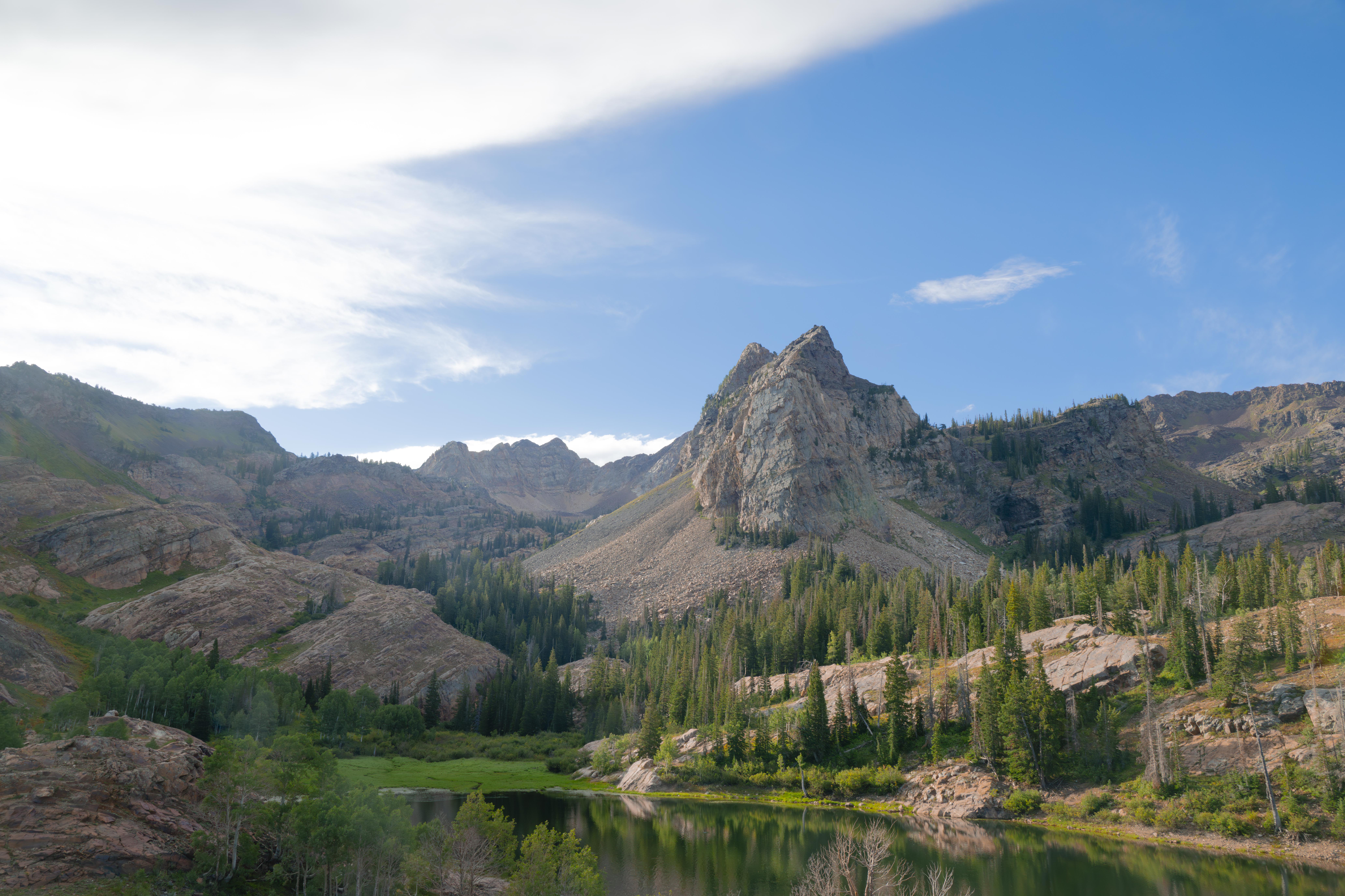Lake Blanche, Big Cottonwood Canyon, UT, Credit Andrew Piskadlo. Rocky mountain peaks above a forested valley with a calm lake reflecting the trees and sky.