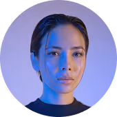 Portrait of a young woman with slicked-back hair and serious expression, illuminated by cool blue lighting.