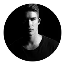 Portrait of a young man with half his face in shadow against a black background.