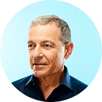 Middle-aged man with short gray hair wearing a dark blue shirt, looking slightly to the side against a light blue background.