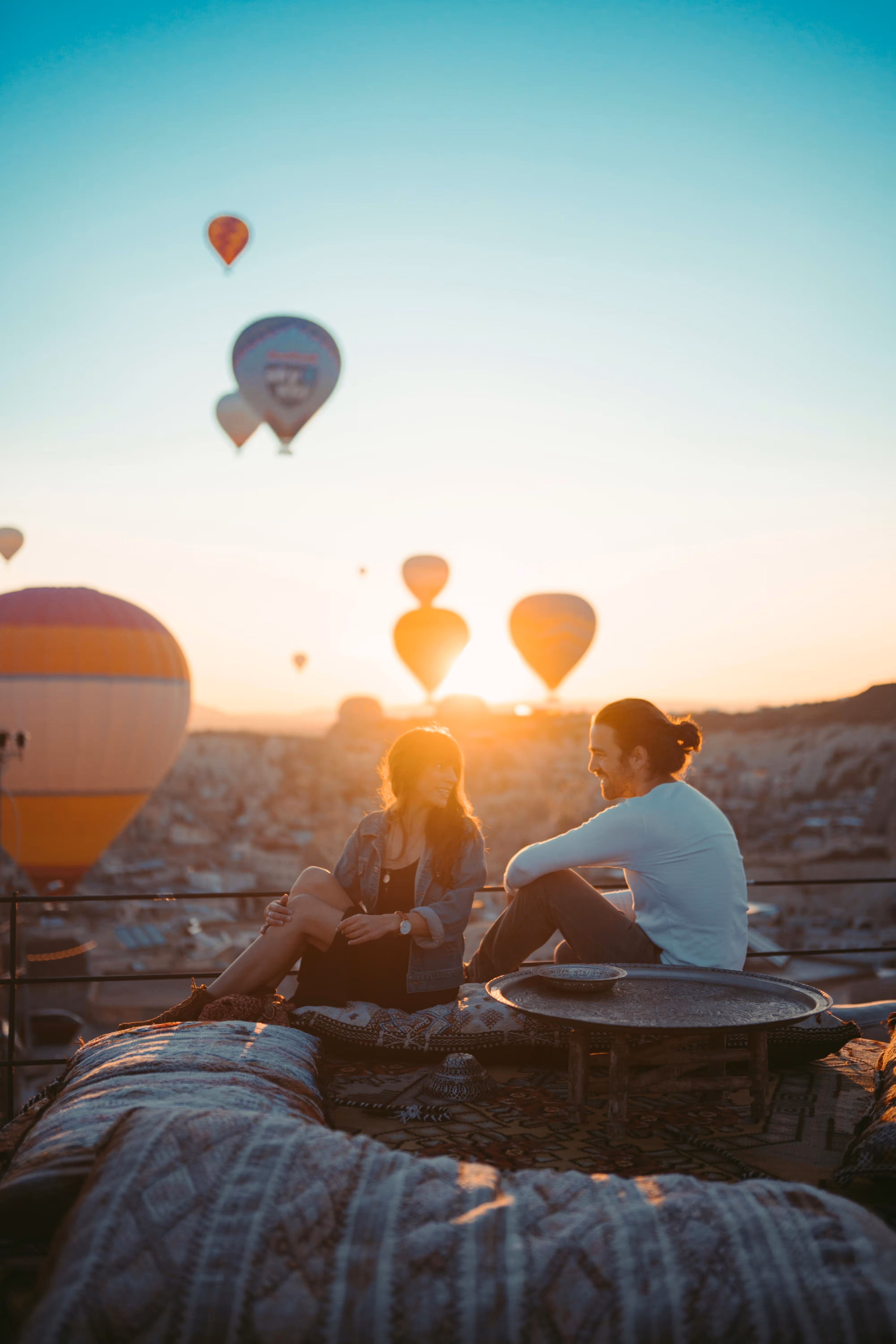 Couple sitting with hot air balloons at sunset