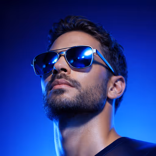 Man with dark hair and beard wearing reflective blue sunglasses against a blue gradient background.