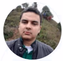 Smiling young man wearing glasses and a black shirt against a light background.