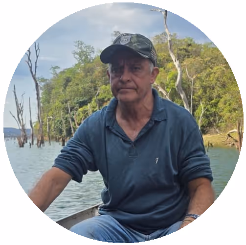 Portrait of a young man with short dark hair and blue eyes wearing a white t-shirt against a light gray background.