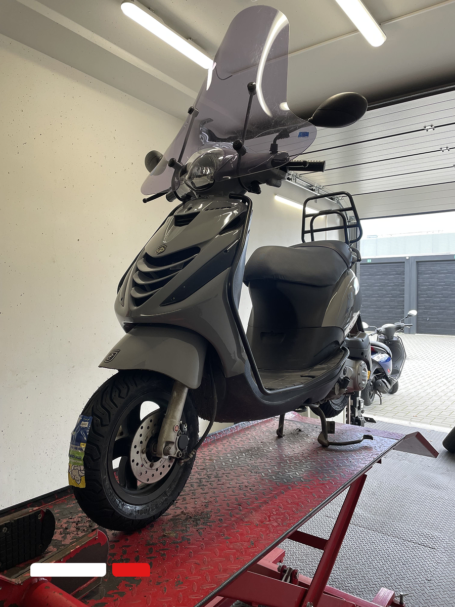 vespa scooter op hefbrug tijdens bandenservice en onderhoud bij Scootzuid