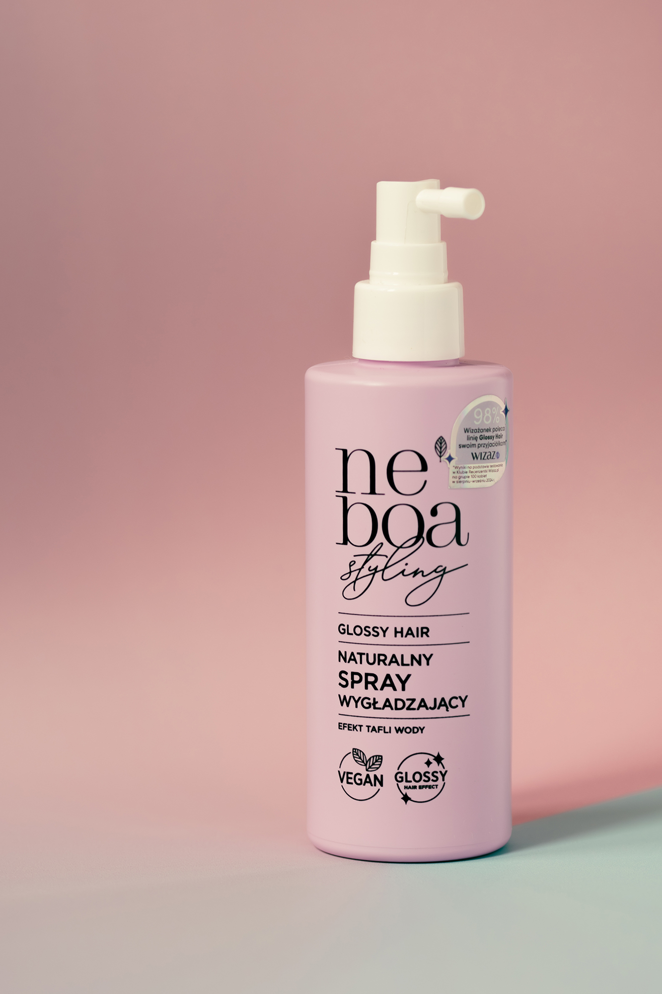 Różowa butelka naturalnego sprayu wygładzającego do włosów Neboa Styling na różowo-niebieskim tle.