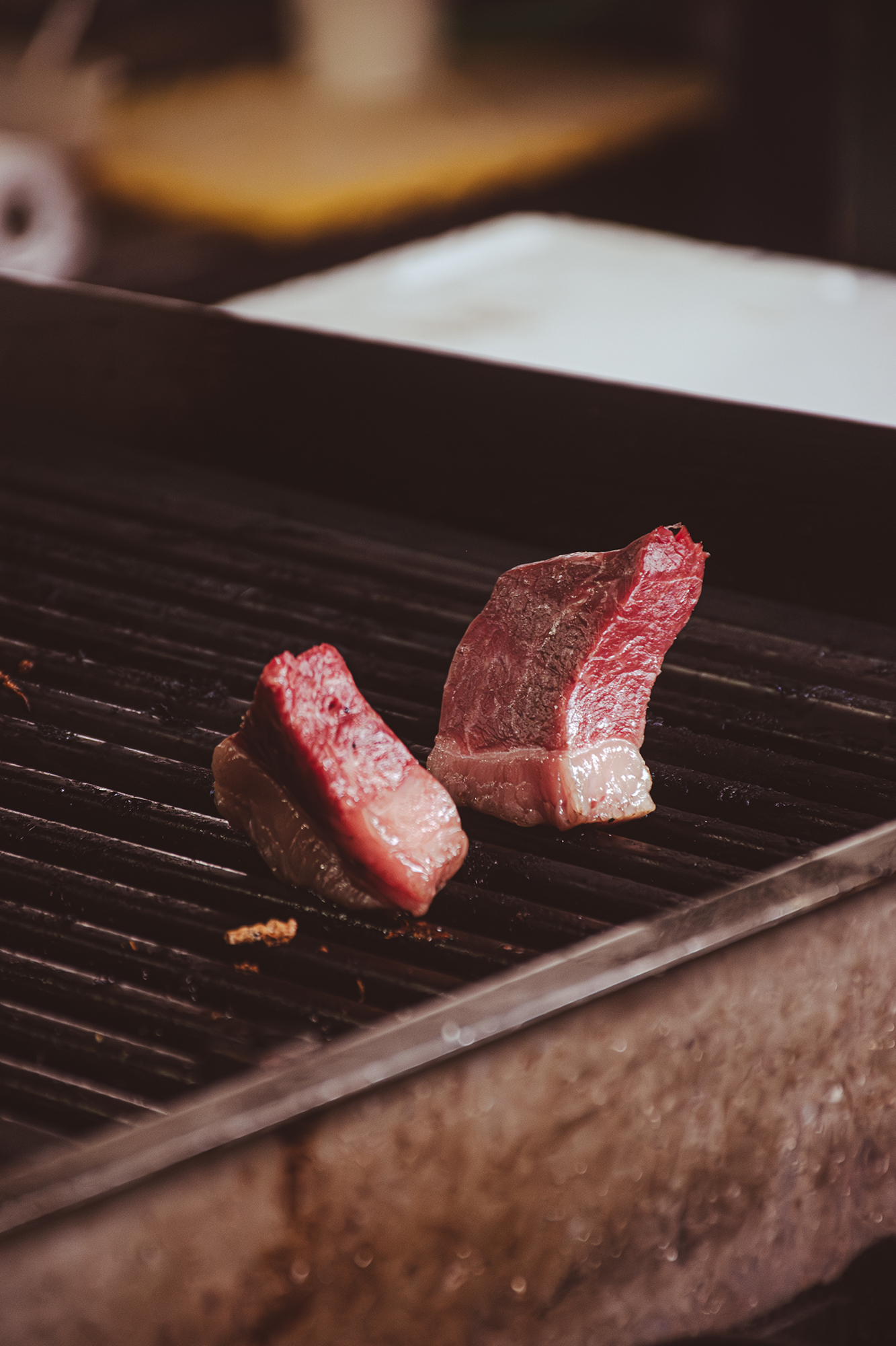 Dwa kawałki surowego mięsa na czystym ruszcie grilla.