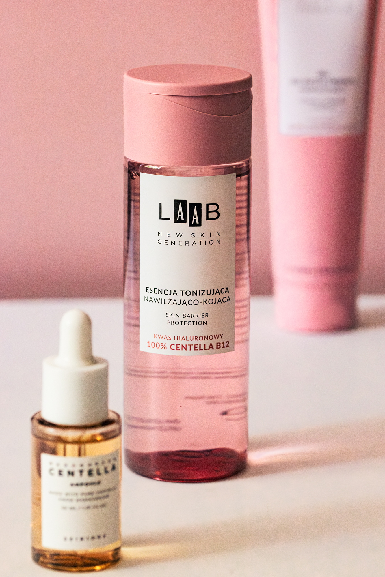 Butelka różowego toniku nawilżająco-kojącego LAAB obok butelki serum z pipetą na białym tle.