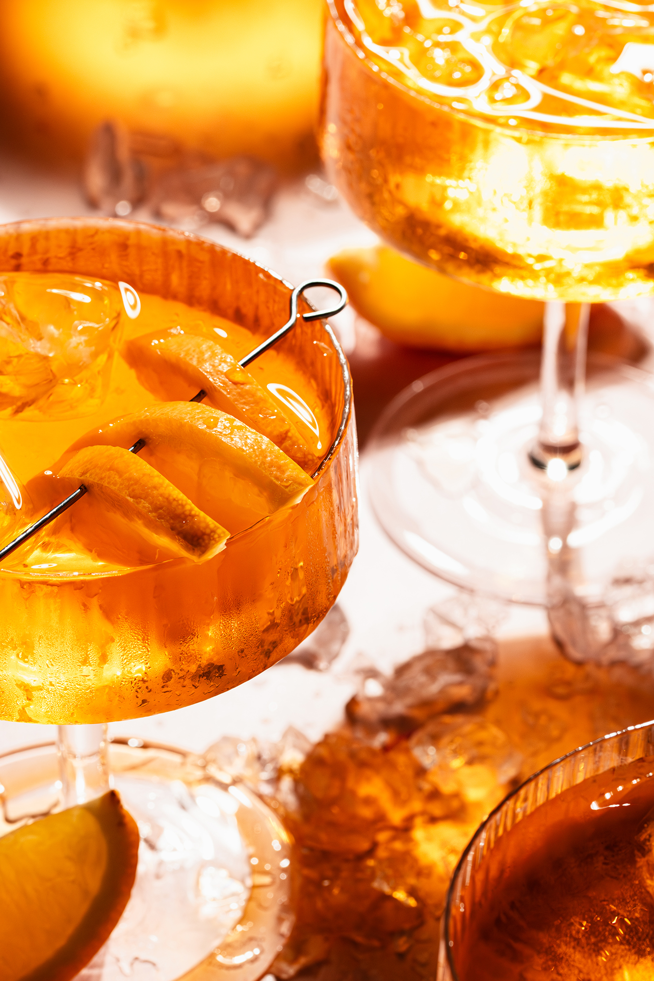 Szklanki z pomarańczowymi drinkami z lodem i plasterkami pomarańczy na metalowym szpikulcu.