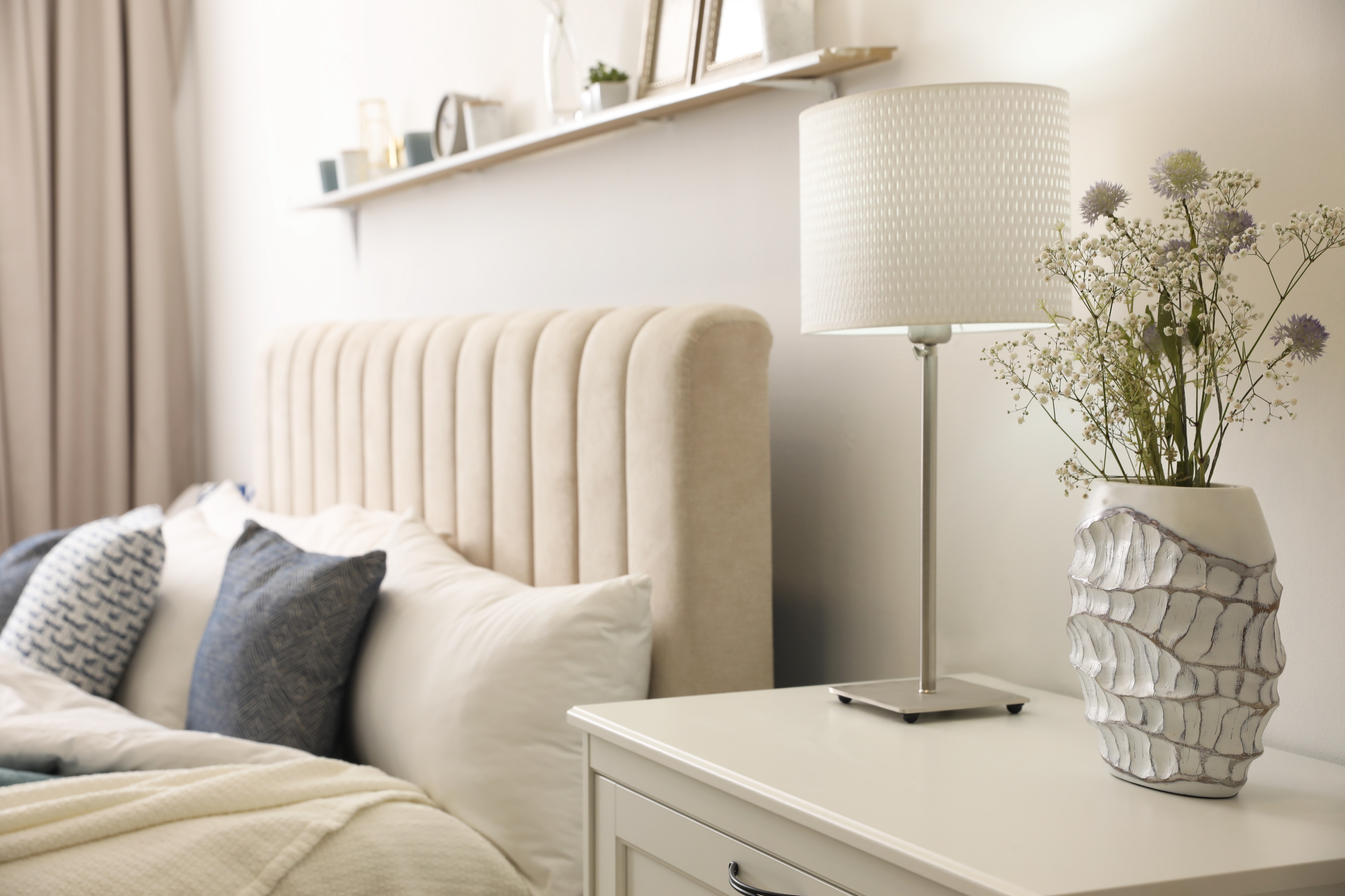 Bedroom with bed with pillows and table decorated with lamp and vase stock image