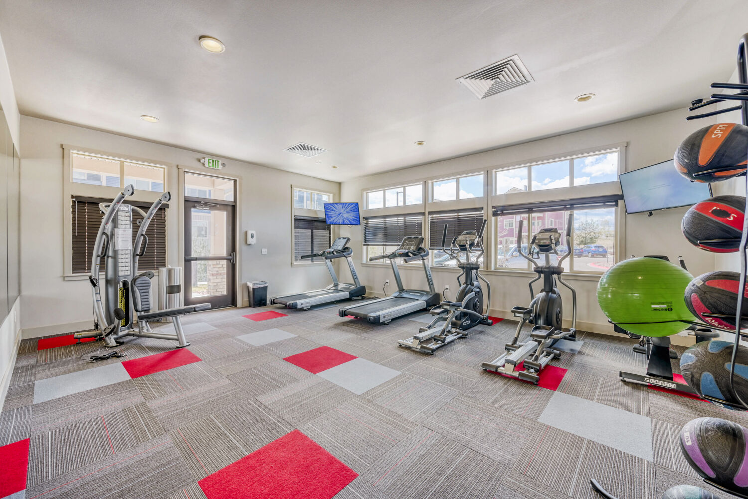 fitness center with red and gray carpet, cardio equipment and television