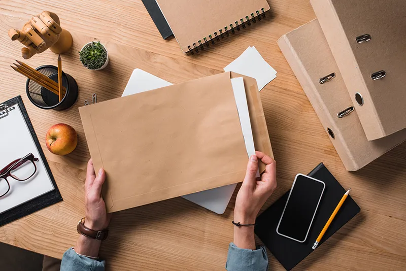 Cropped shot of businessman holding envelope with documents at workplace