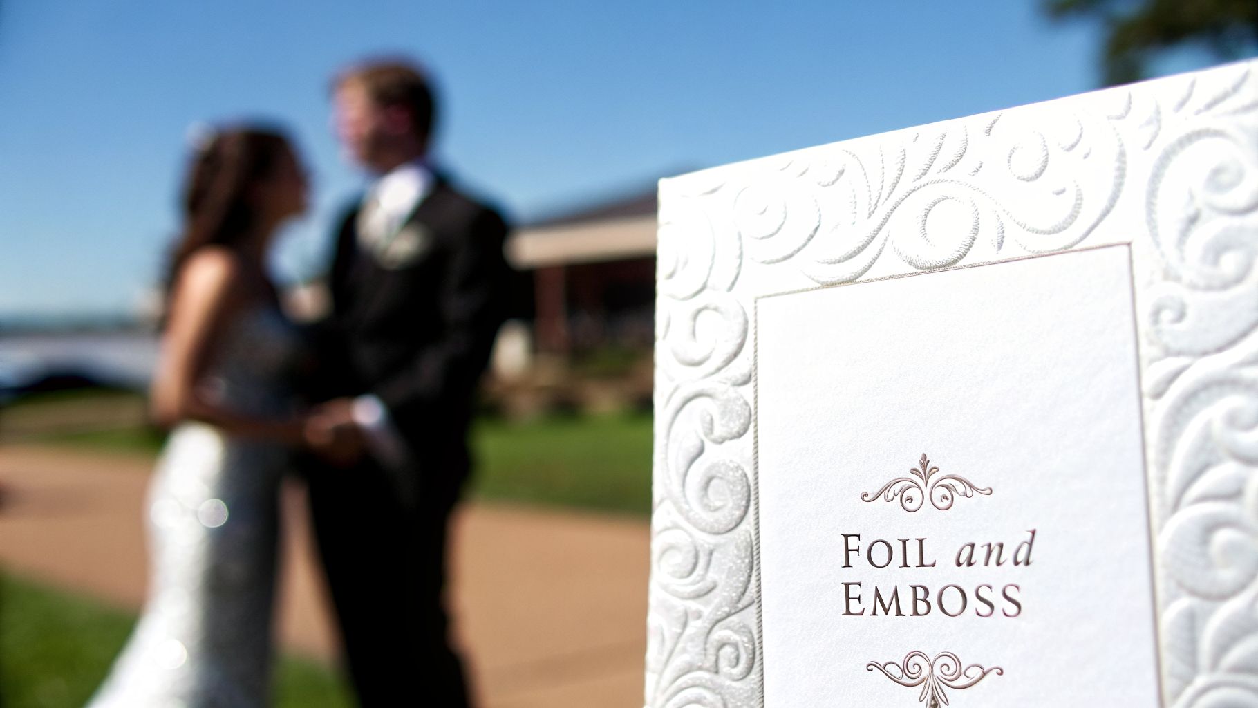Elegant wedding invitation card displaying 'FOIL and EMBOSS' text, with a blurred bride and groom.
