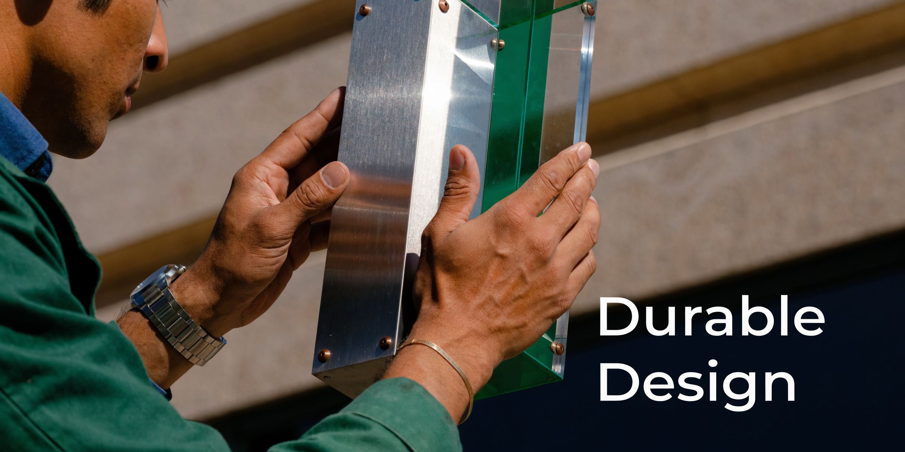 A person holding a modern architectural signage piece with metallic and green glass materials for business.