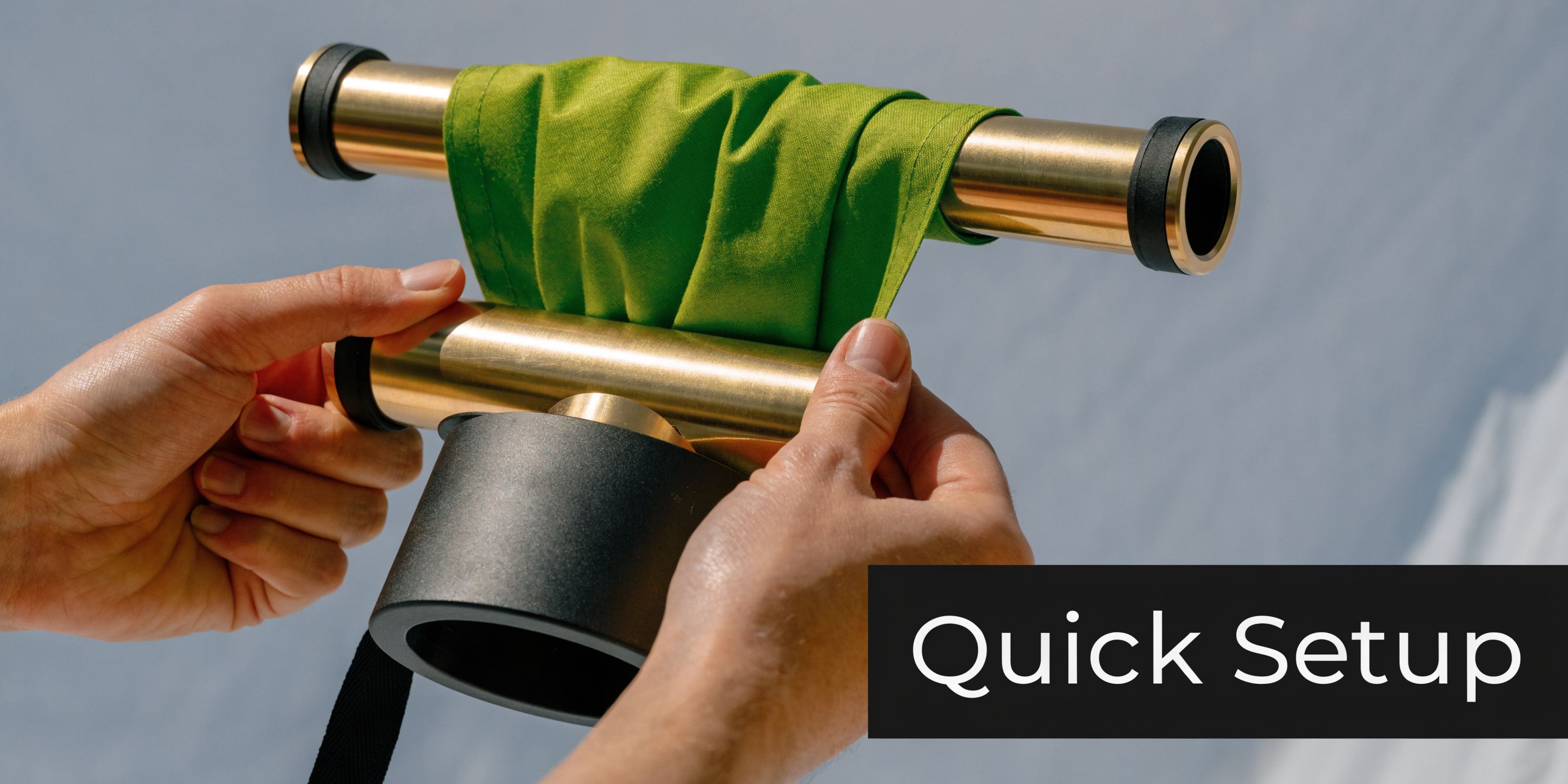 A pair of hands setting up a portable roll up banner with brass poles and green fabric.