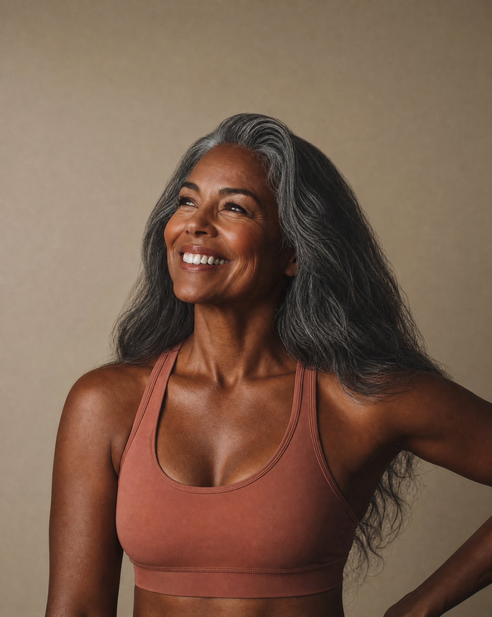 Smiling woman with gray hair in rust sports bra