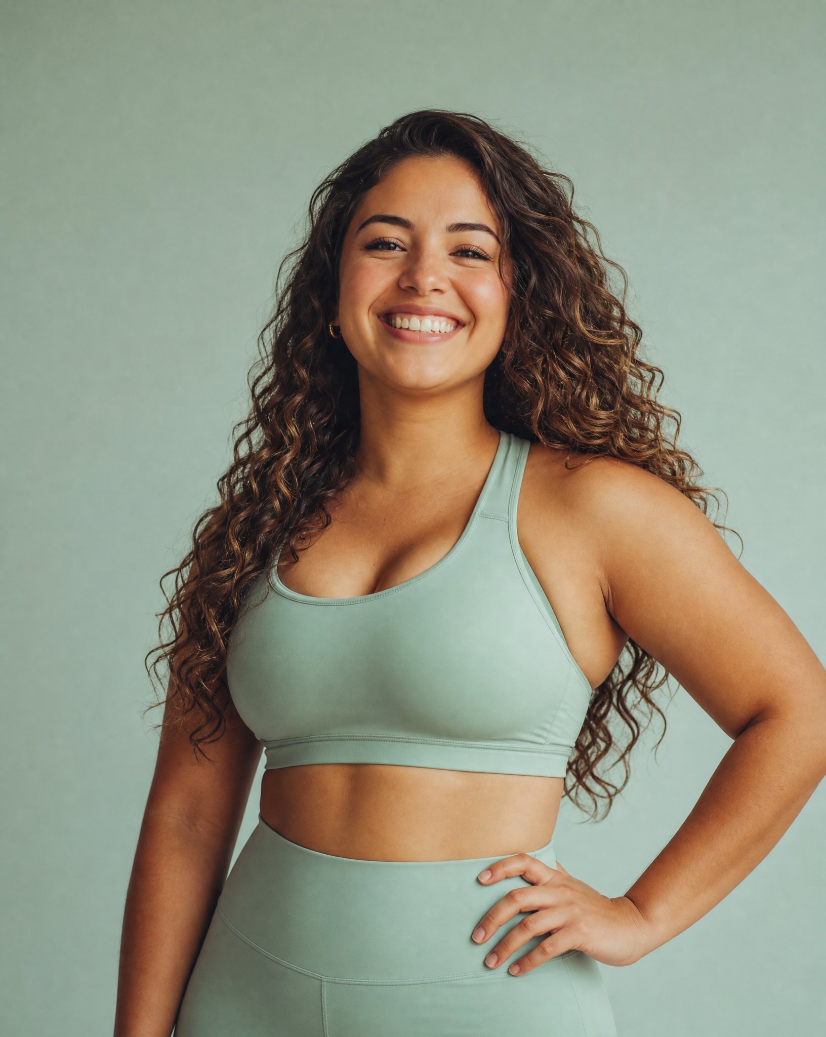 Smiling woman with curly hair in sage athletic wear