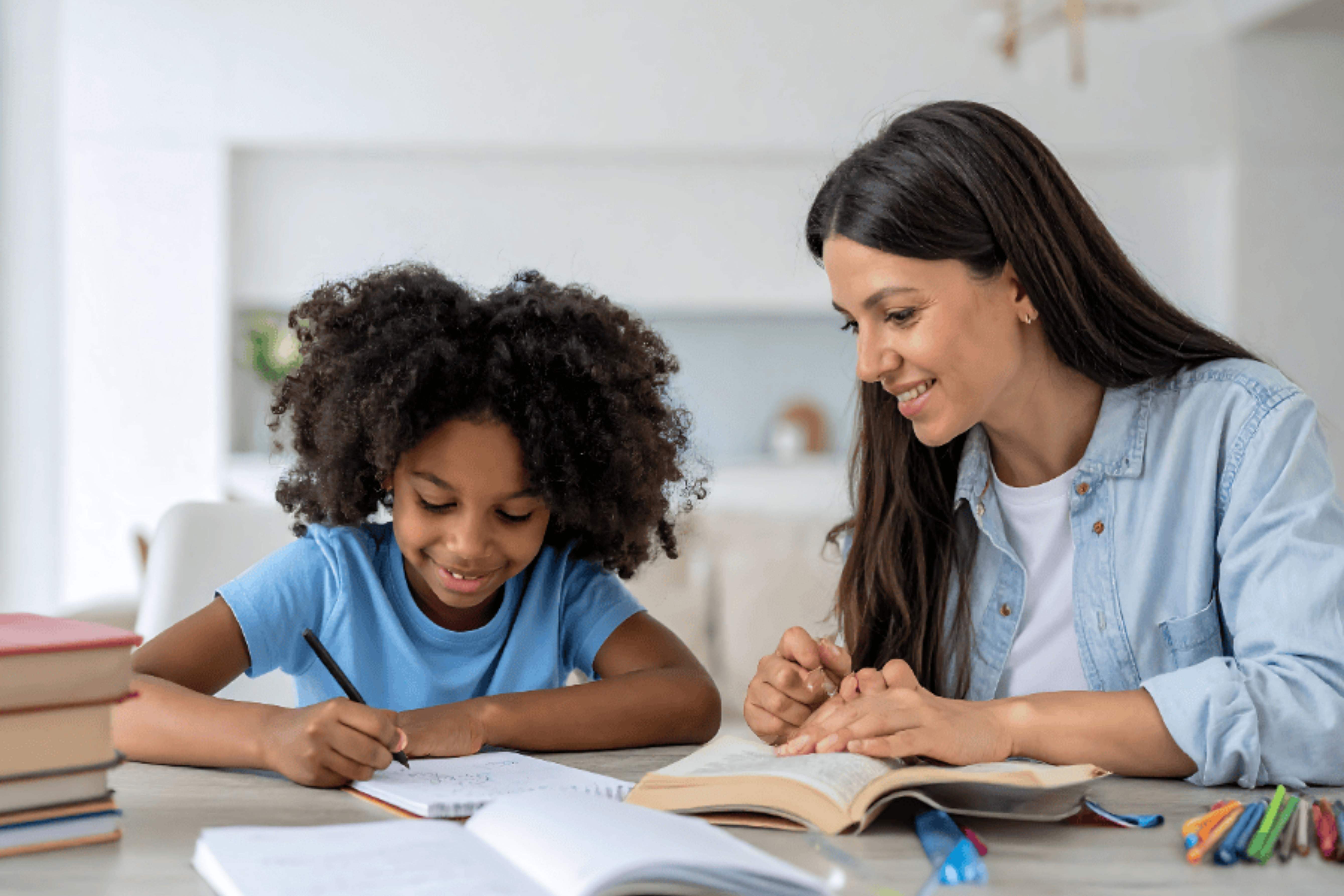 Adulte qui fait les devoirs avec un enfant, assis à la table avec des cahiers