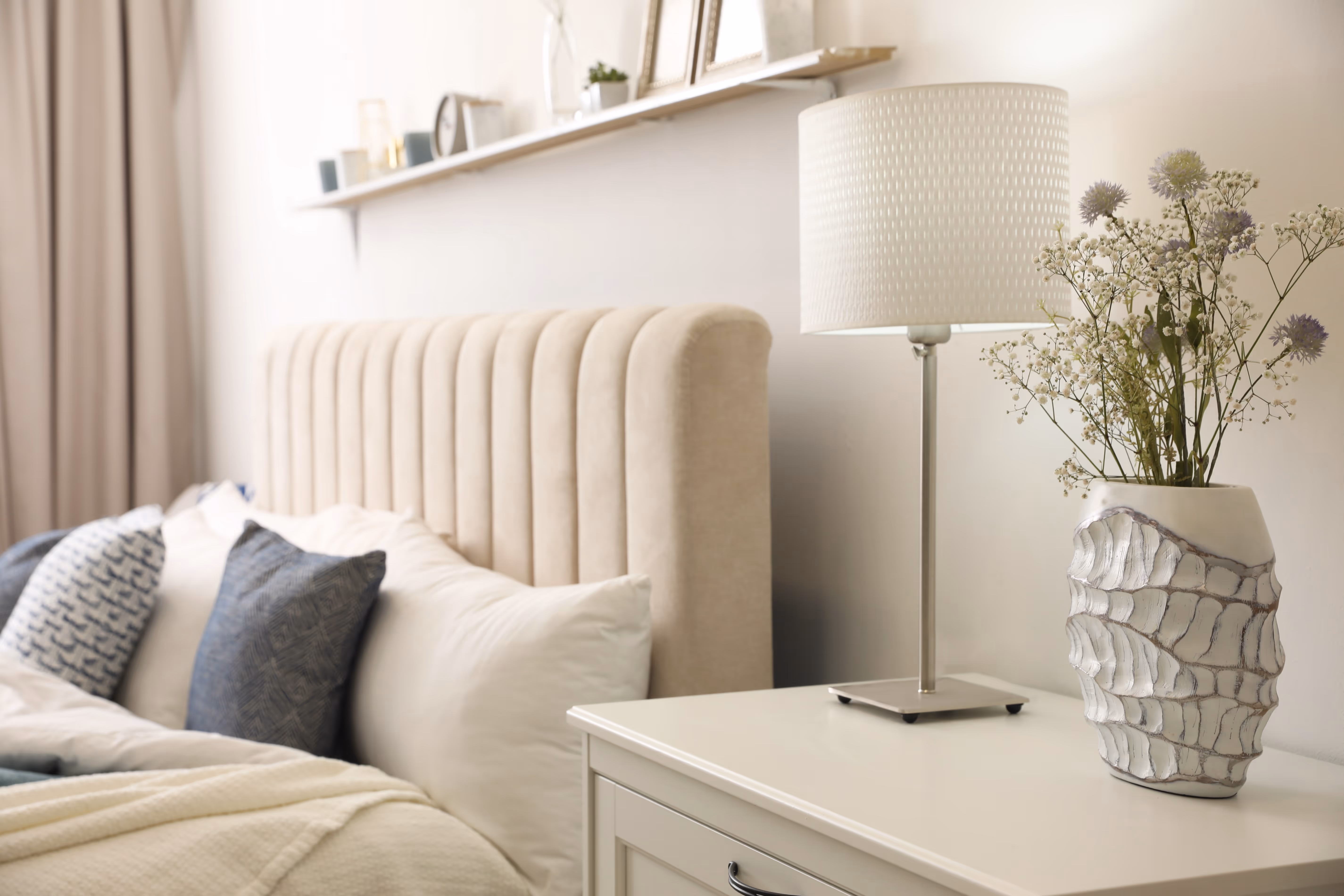 Bedroom with bed with pillows and table decorated with lamp and vase stock image