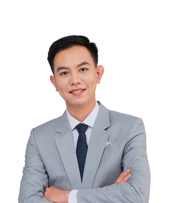 Smiling young man in a gray suit and blue polka dot tie with arms crossed.