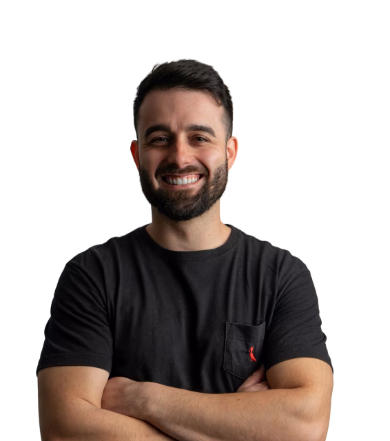 Smiling man with beard and short hair wearing a black t-shirt with crossed arms.