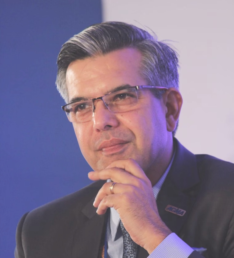 Man with glasses, gray-streaked hair, and wearing a suit, resting his chin thoughtfully on his hand.