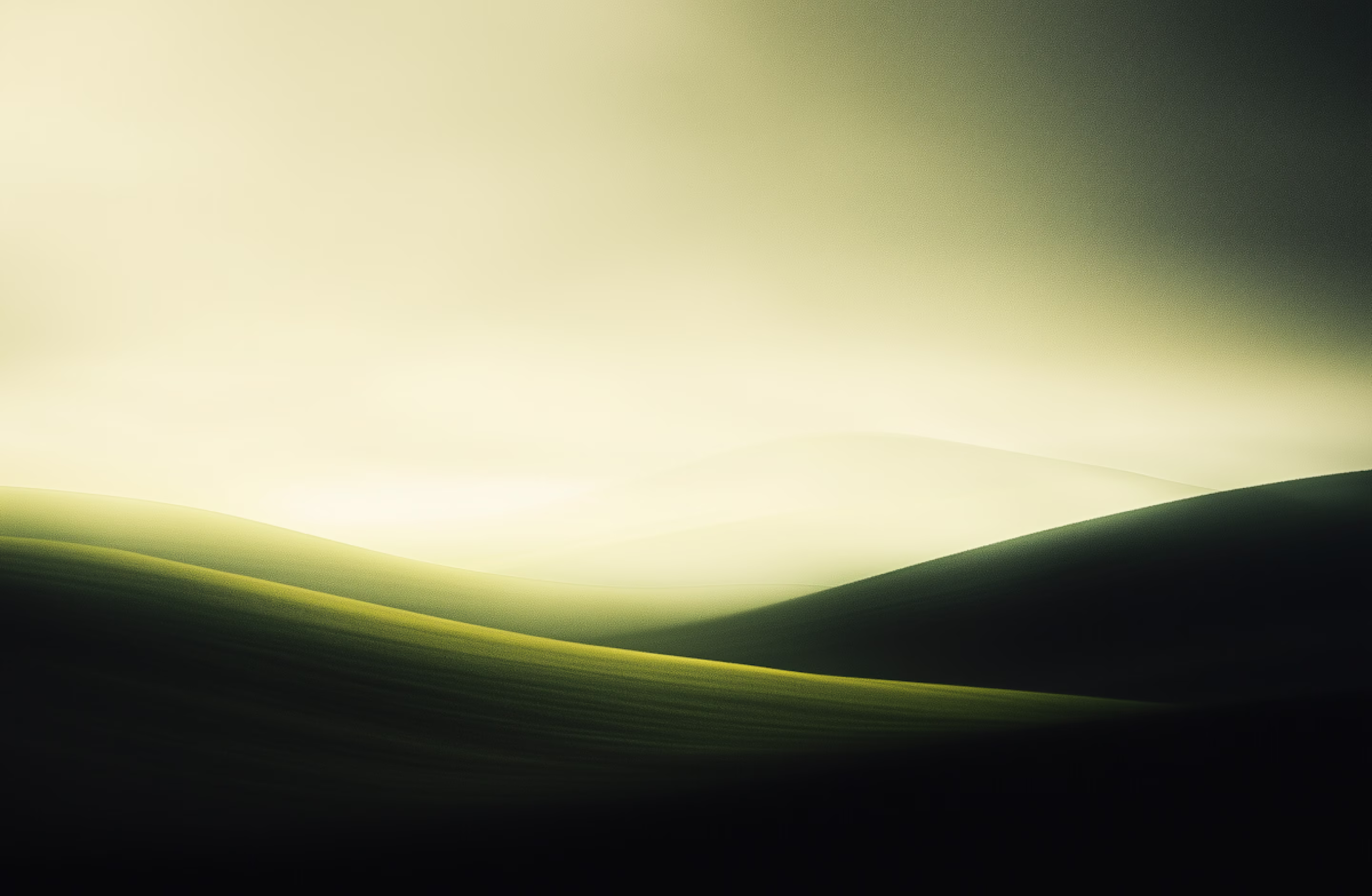 Softly lit rolling hills with green grass under a foggy, yellow-green sky.