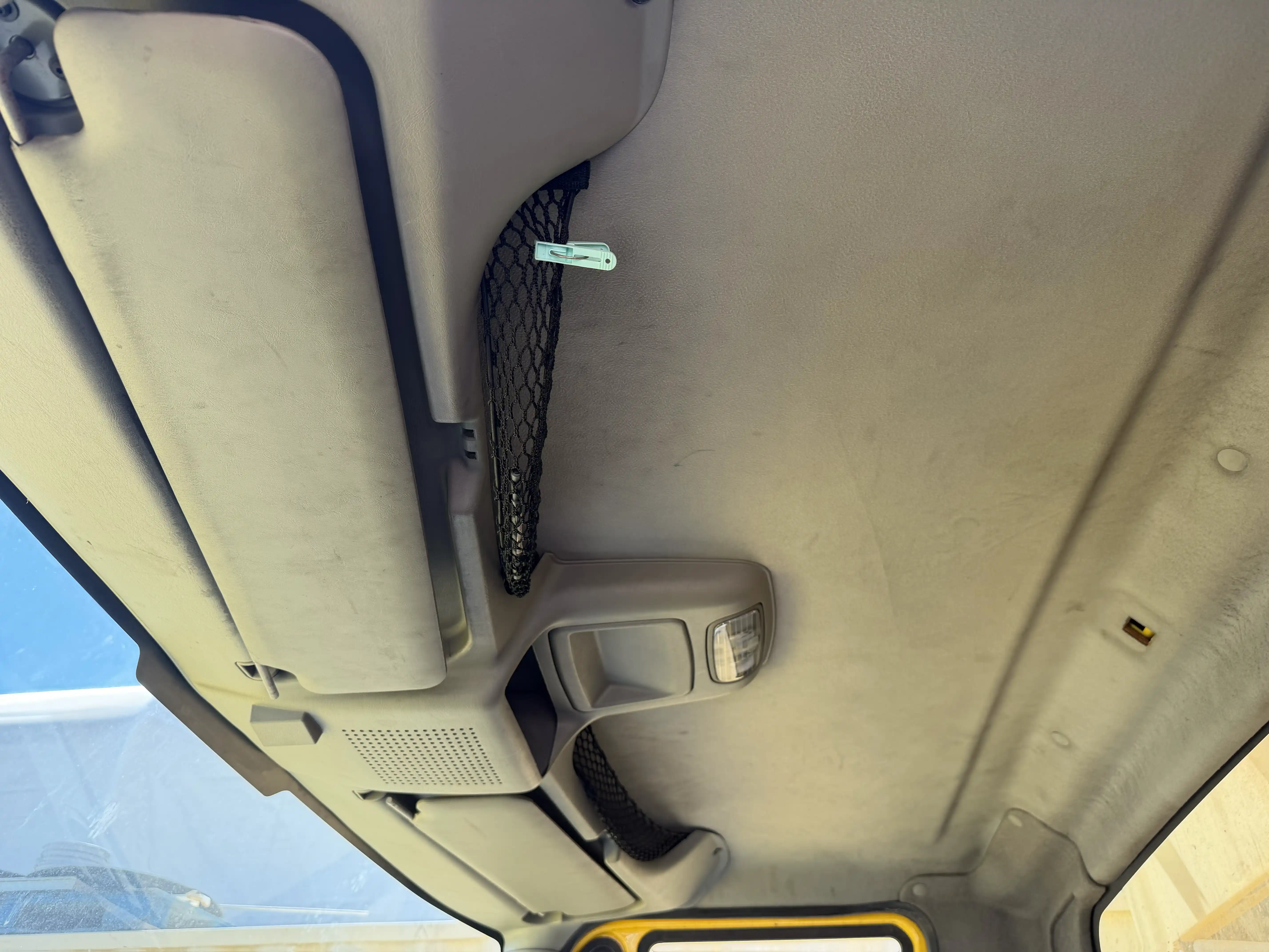 Cab headliner with overhead storage netting and sun visors