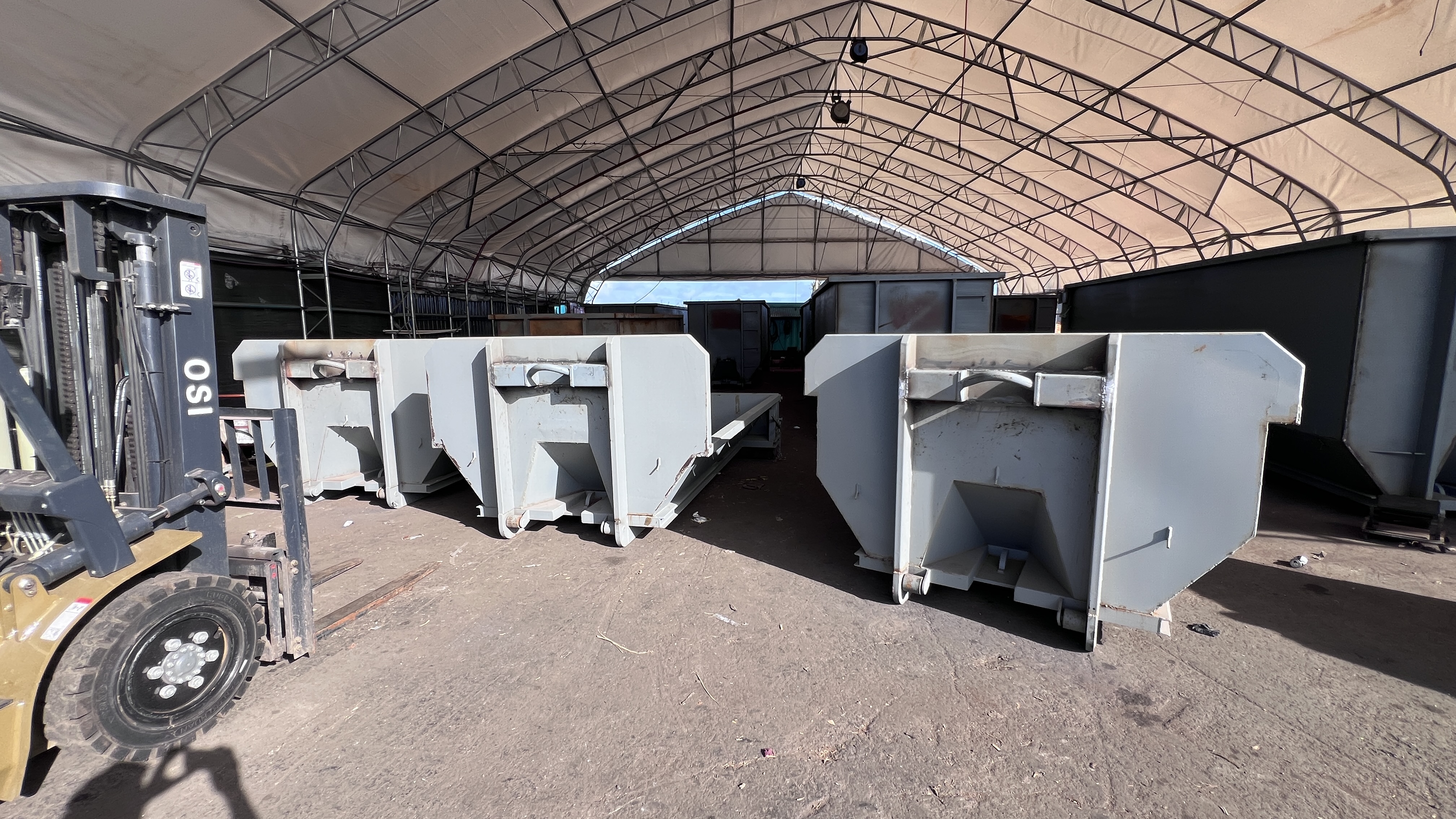 New batch of dumpsters staged under the shop tent with a forklift