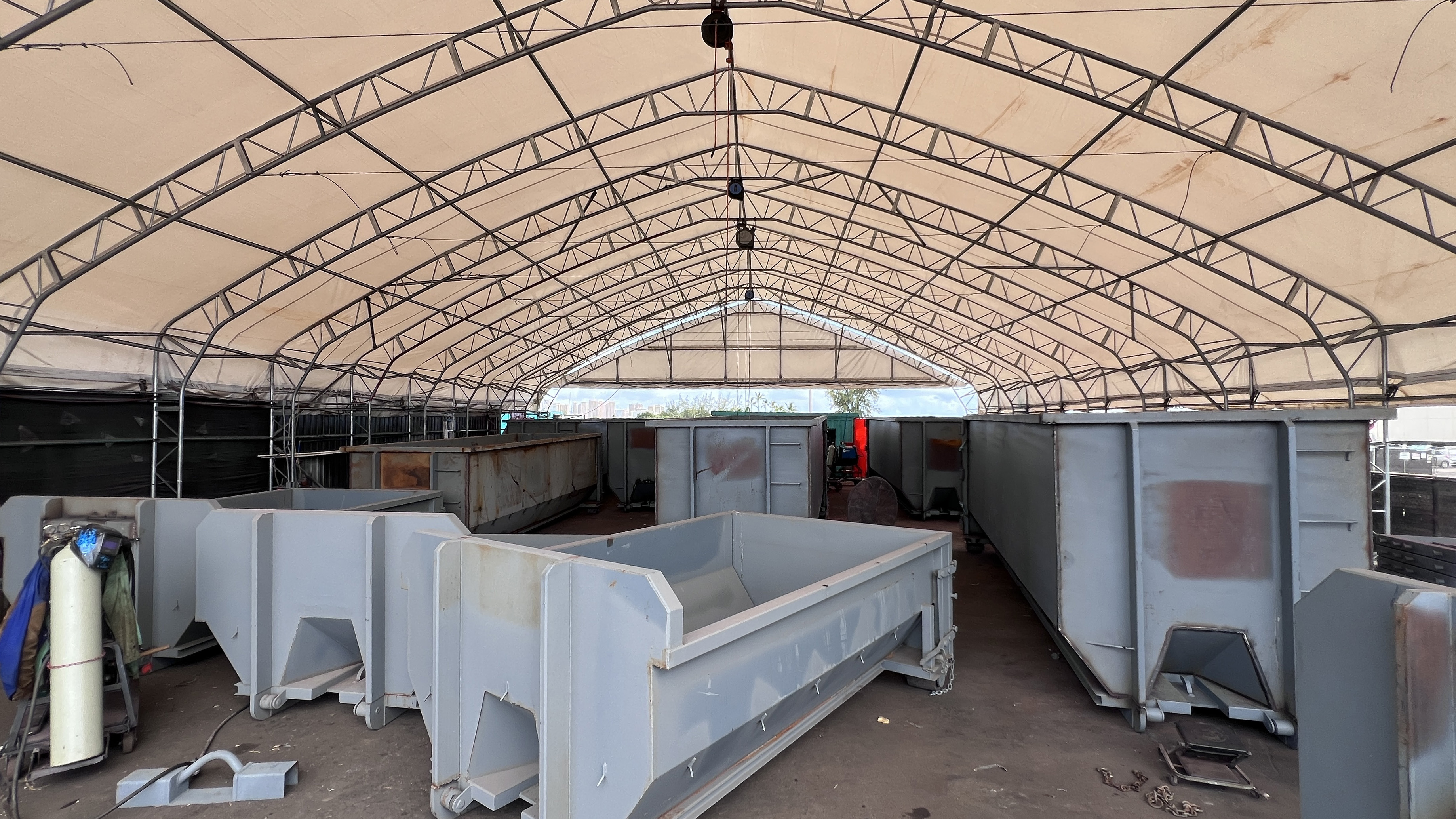 Multiple dumpsters and hoppers lined up under the shop tent