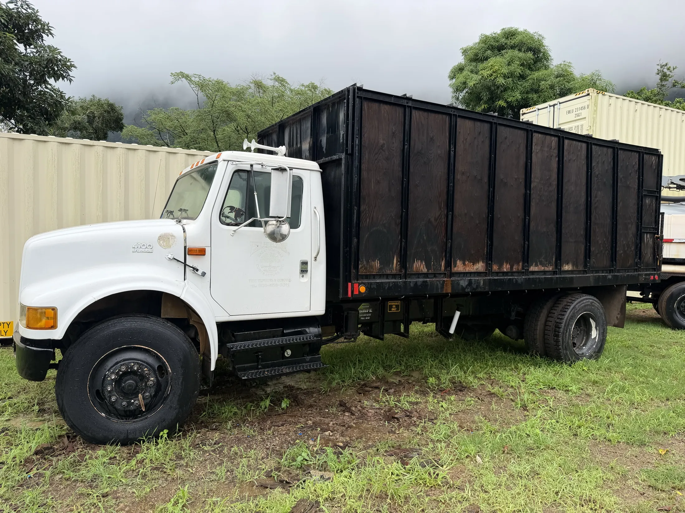 Driver side of the 2000 International 4900 with the wood-sided steel-framed dump bed and dual rear wheels