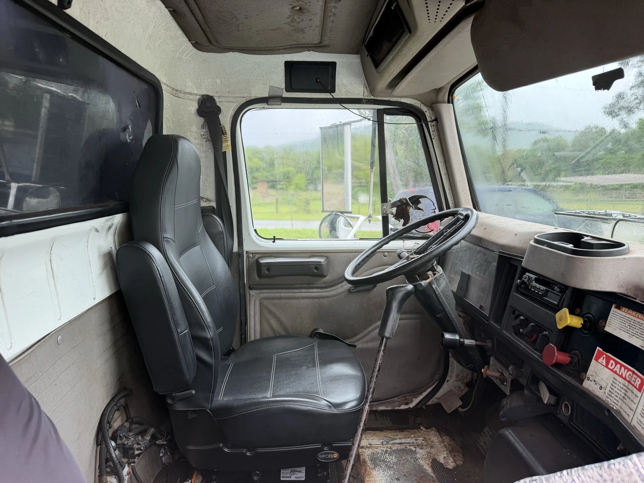 Cab interior with black high-back driver seat, steering wheel, dash and shifter