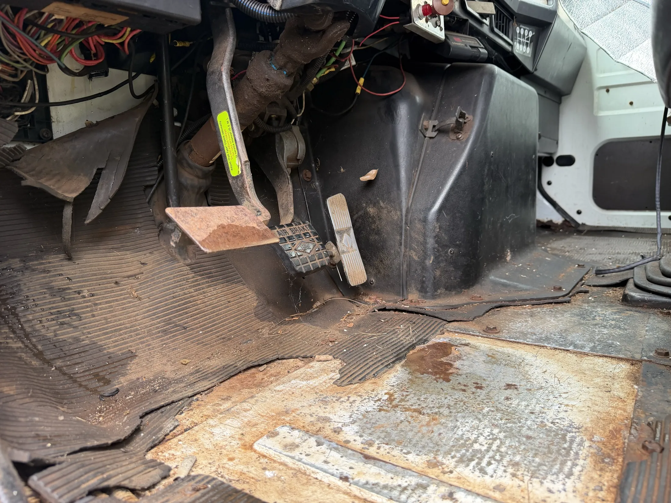 Cab floor with clutch, brake and accelerator pedals and a worn floor mat