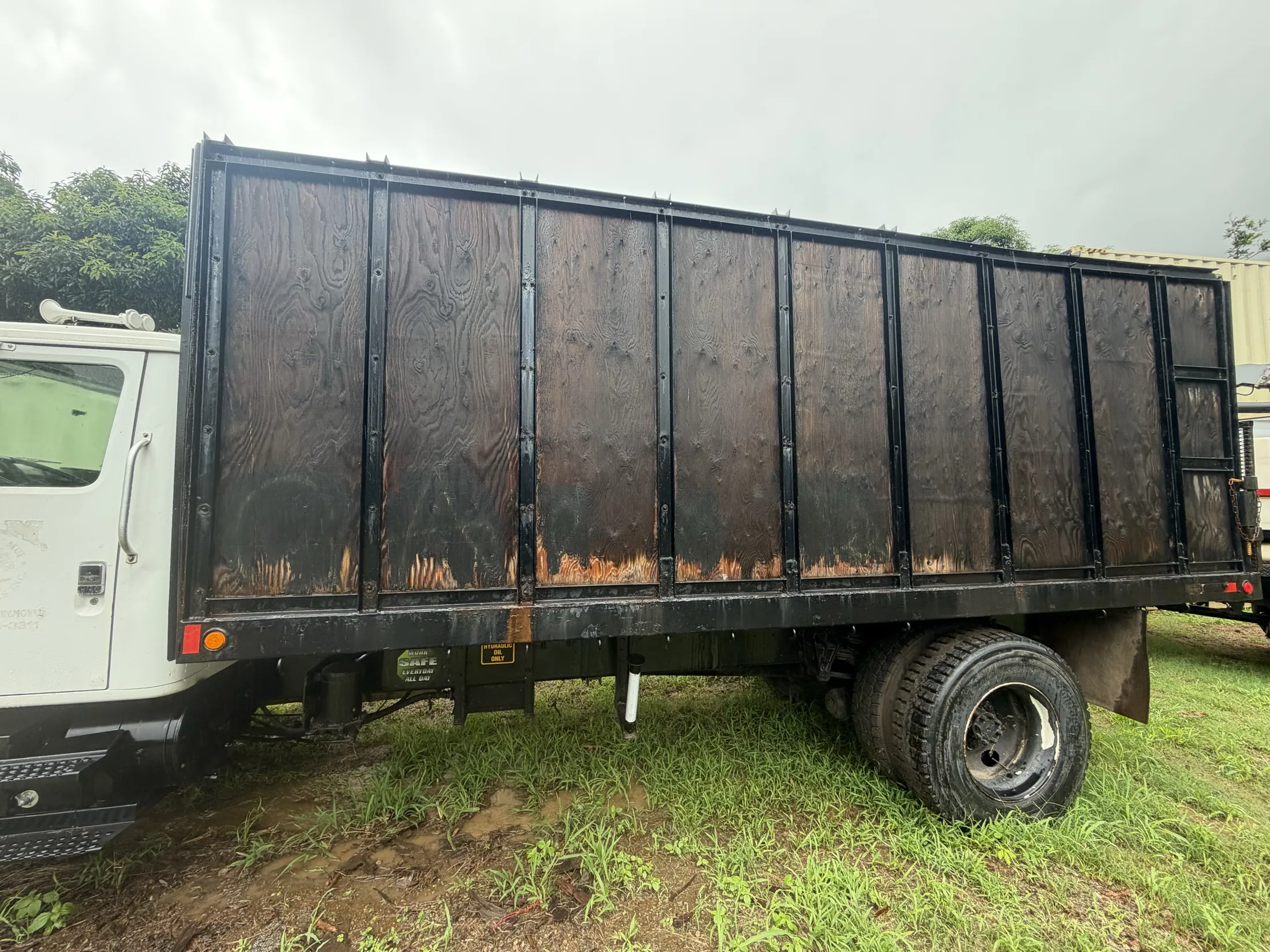Close-up of the dump bed's wood side panels and steel framing above the dual rear tires