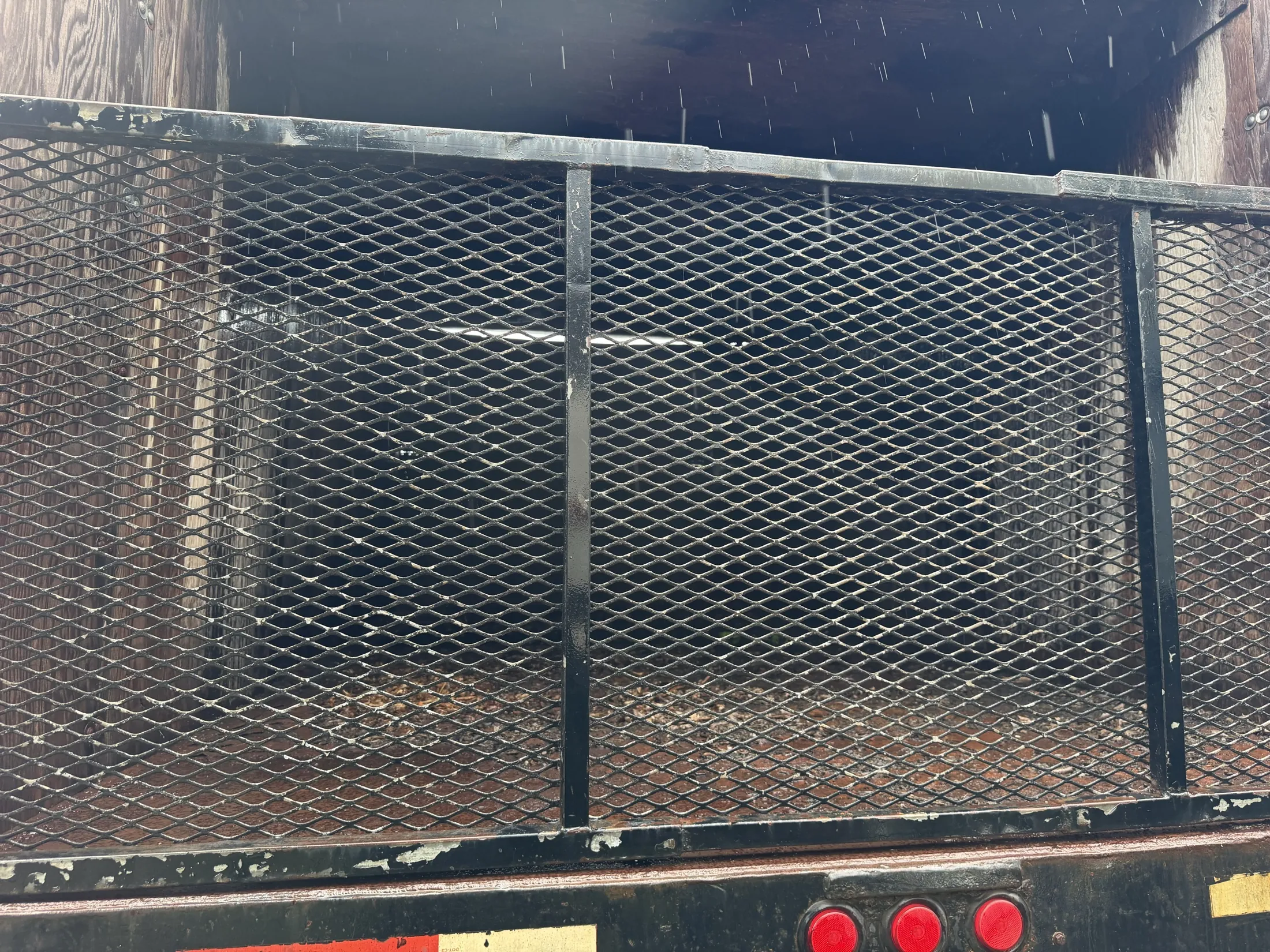 Rear of the dump bed showing the steel mesh gate and tail lights