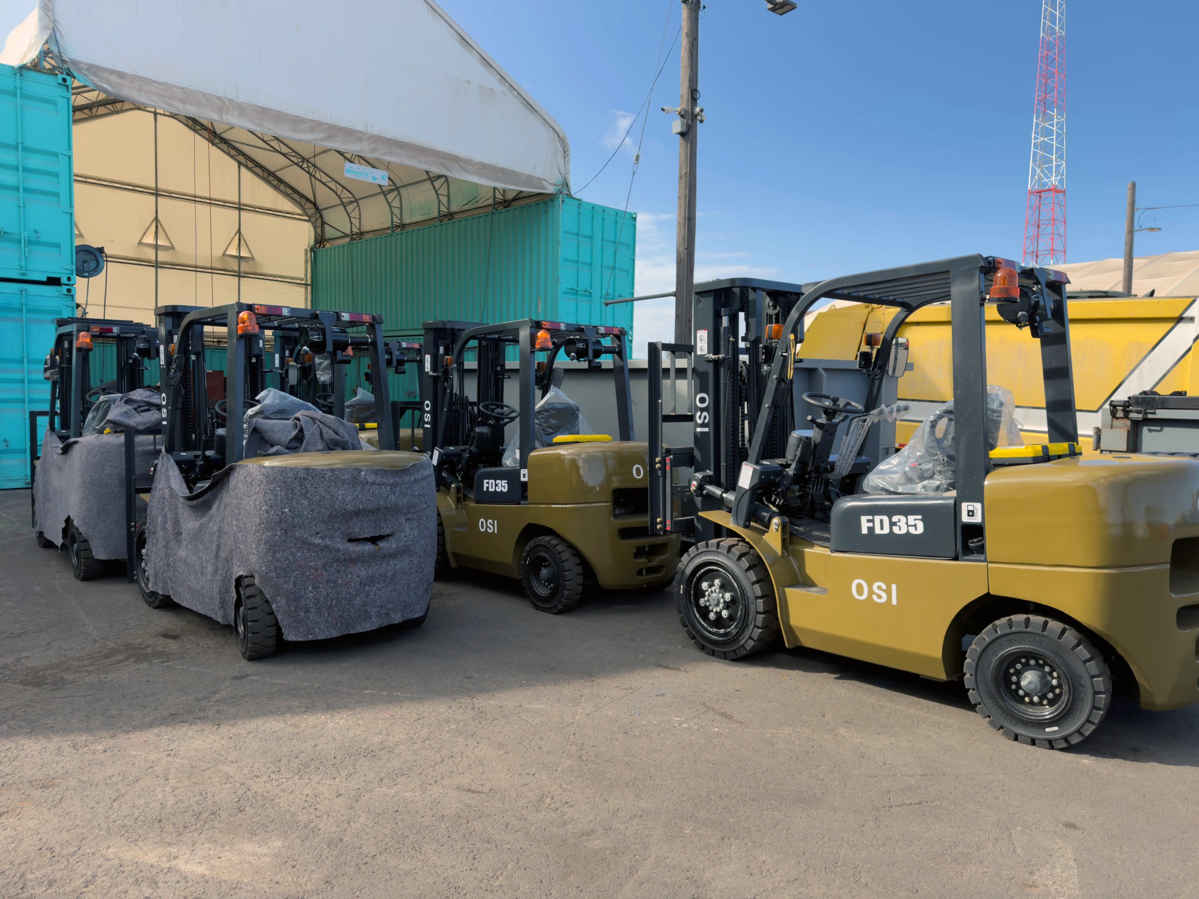 Row of OSI FD35 forklifts in the HIWASTE MFG yard next to a container tent