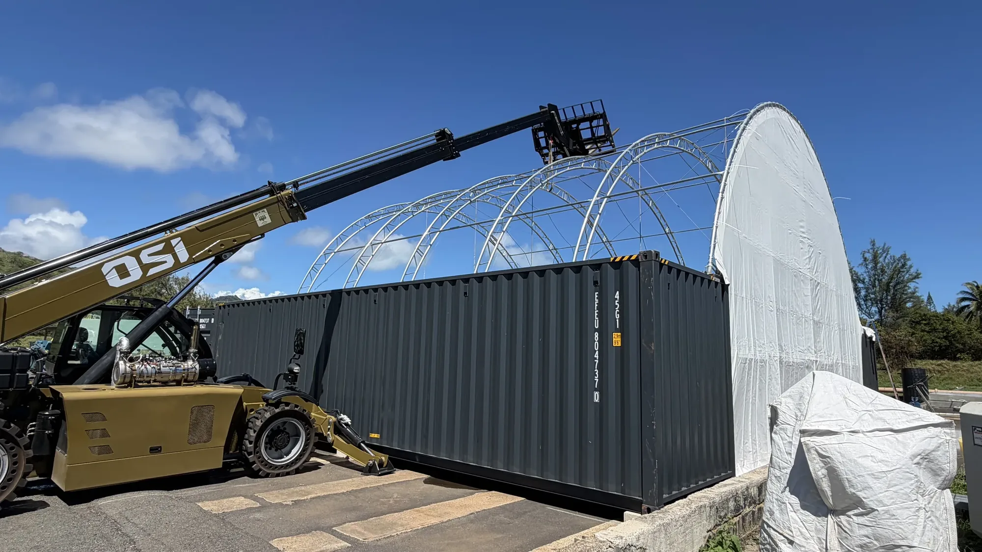 OSI telehandler boom reaching over a 40x40 container tent frame on Oahu