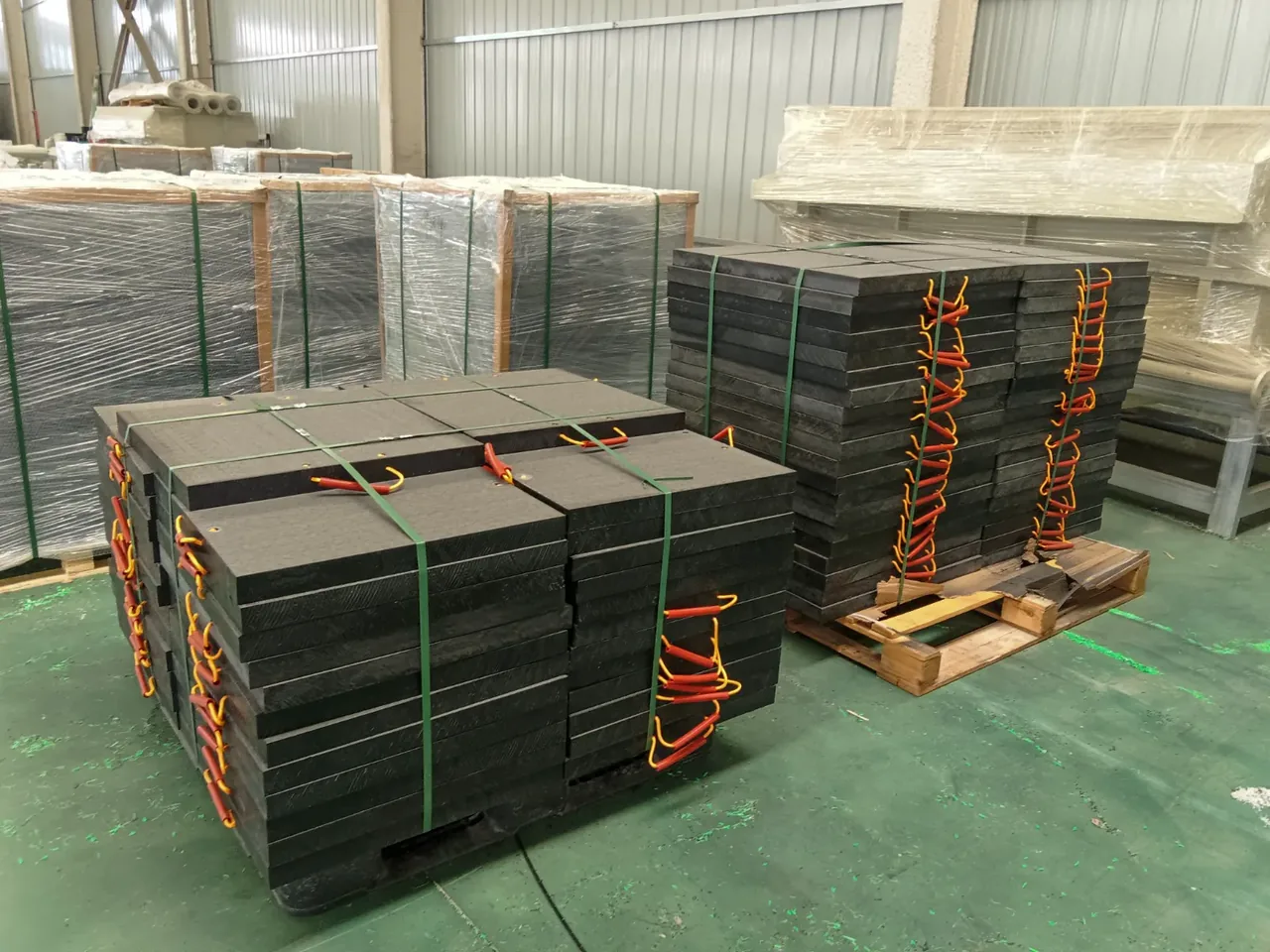 Stacks of HIWASTE outrigger pads with rope handles on pallets