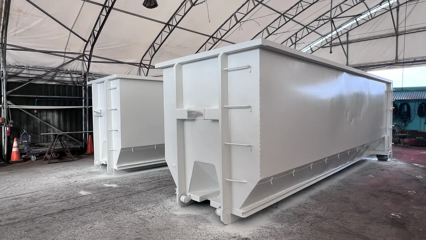 Freshly painted roll-off dumpsters in the HIWASTE MFG shop in Honolulu